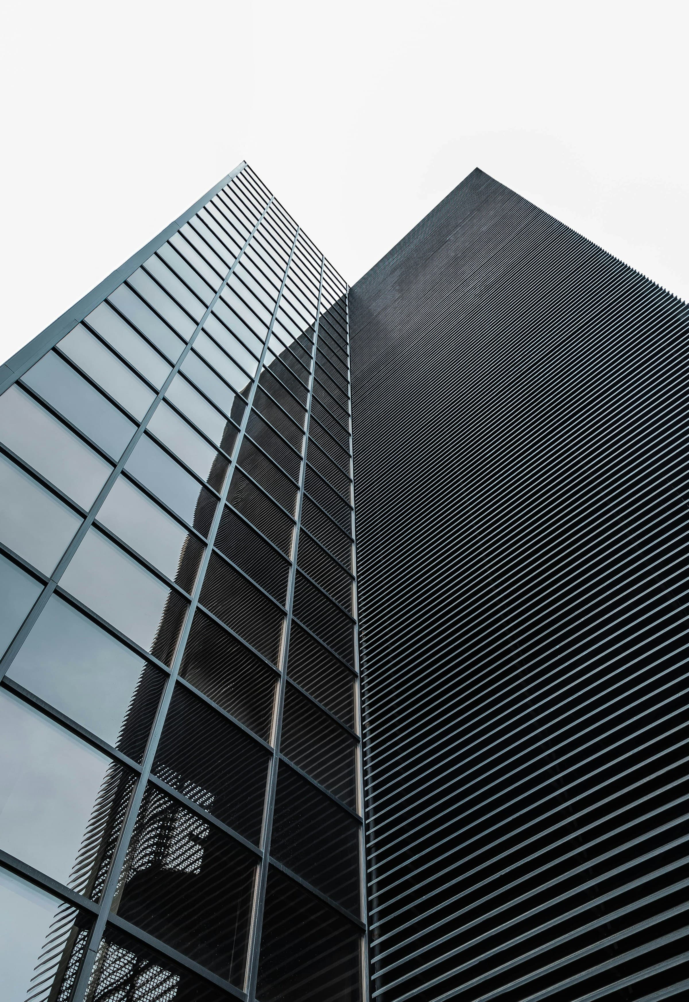 Low angle view of a modern black glass office building rising against a pale sky.